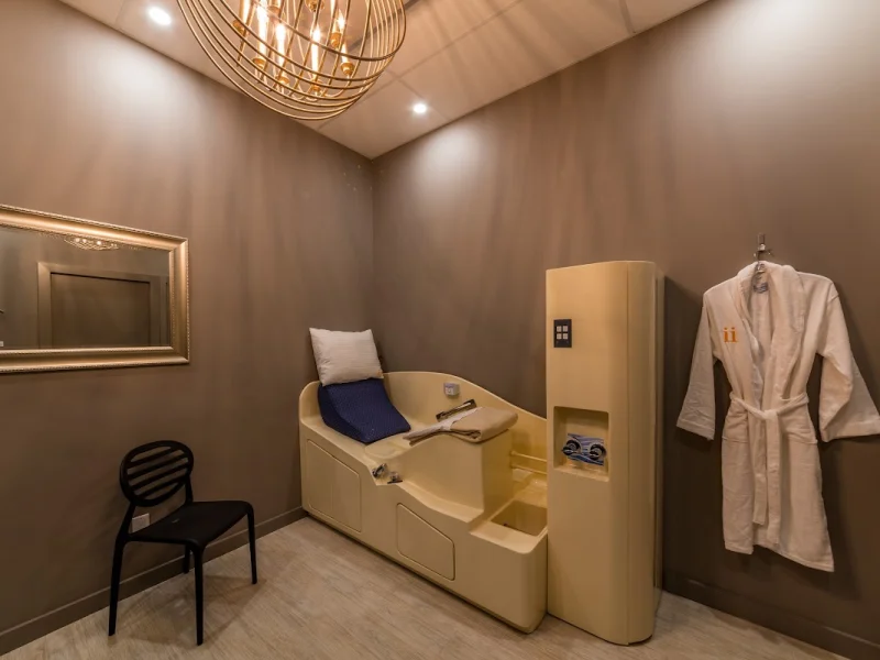 Private treatment room with spa chair, robe, and elegant chandelier lighting