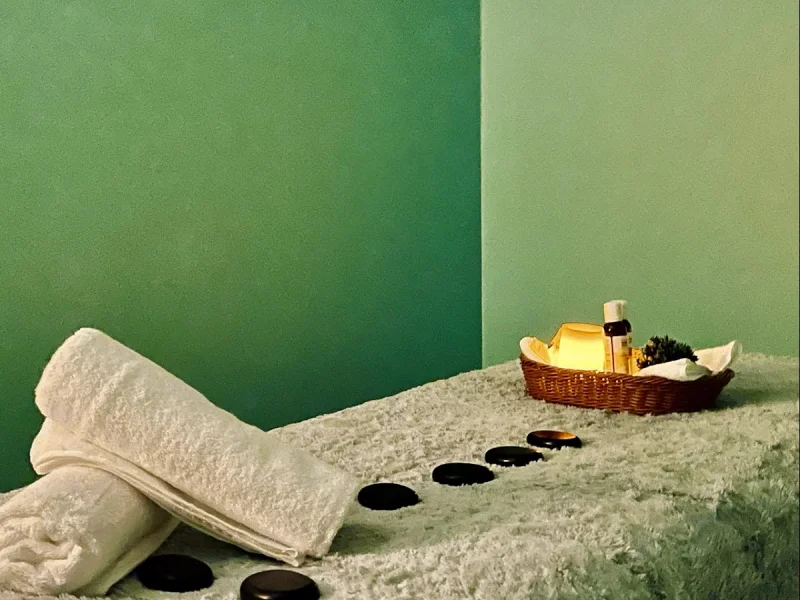 Serene spa treatment room with green walls, massage stones, and spa essentials