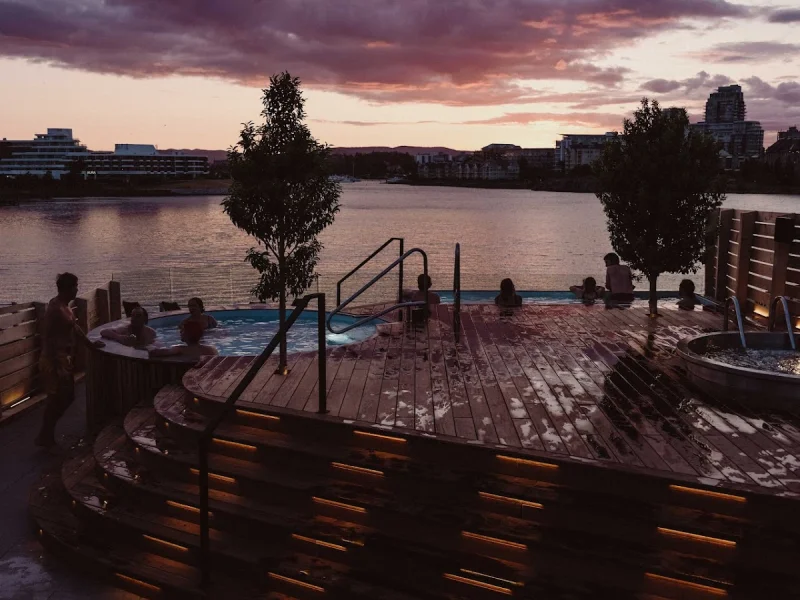 Rooftop hot tub and sauna deck at sunset with waterfront views