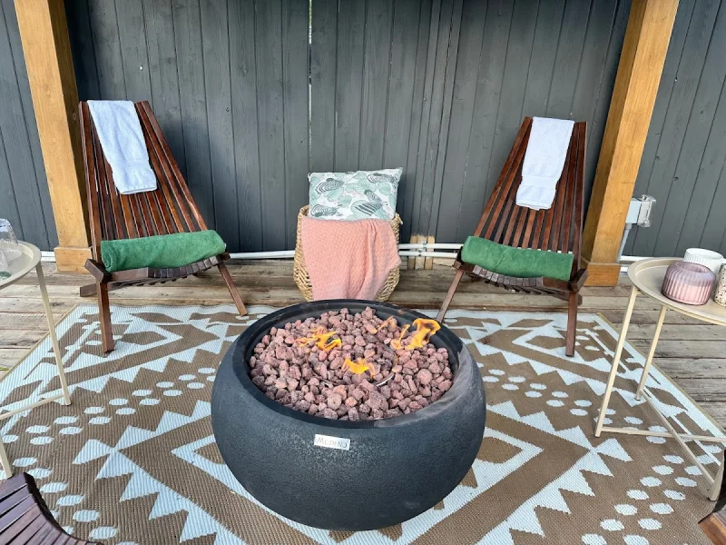 Cozy fire pit seating area under a covered pergola with towels and side tables.