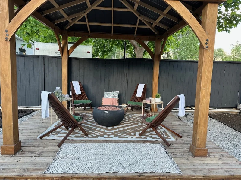 Outdoor lounge gazebo with fire pit, deck chairs, and shaded relaxation area.