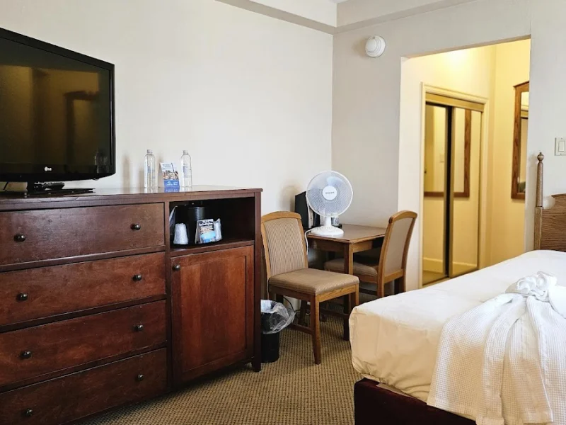 Simple guest room with bed, TV, and compact seating area