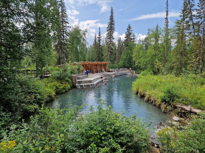 Panoramic forest hot spring with wooden pavilion and clear green water