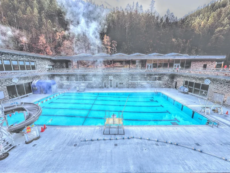 Steaming outdoor lap pool at Radium Hot Springs with stone lodge architecture