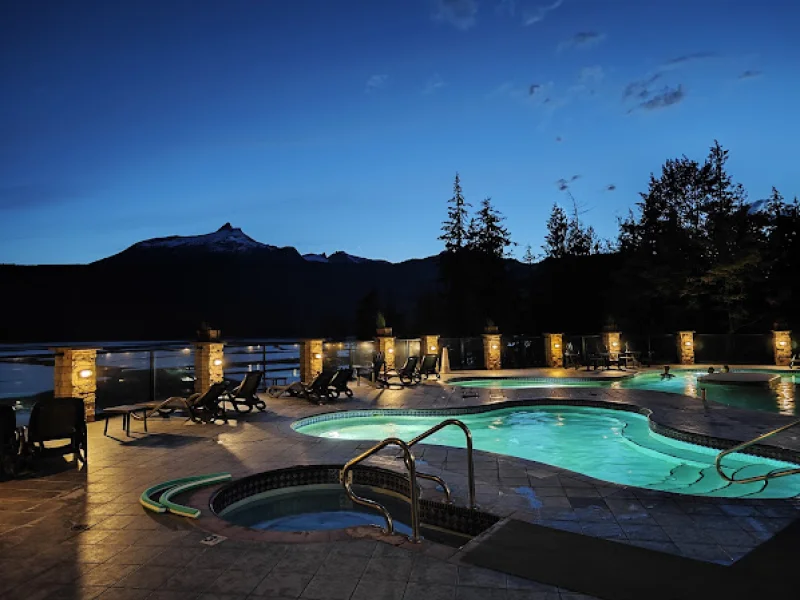 Illuminated outdoor hot spring pools with mountain backdrop at dusk