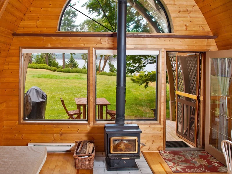 Cabin lounge with wood stove, panoramic windows, and outdoor views
