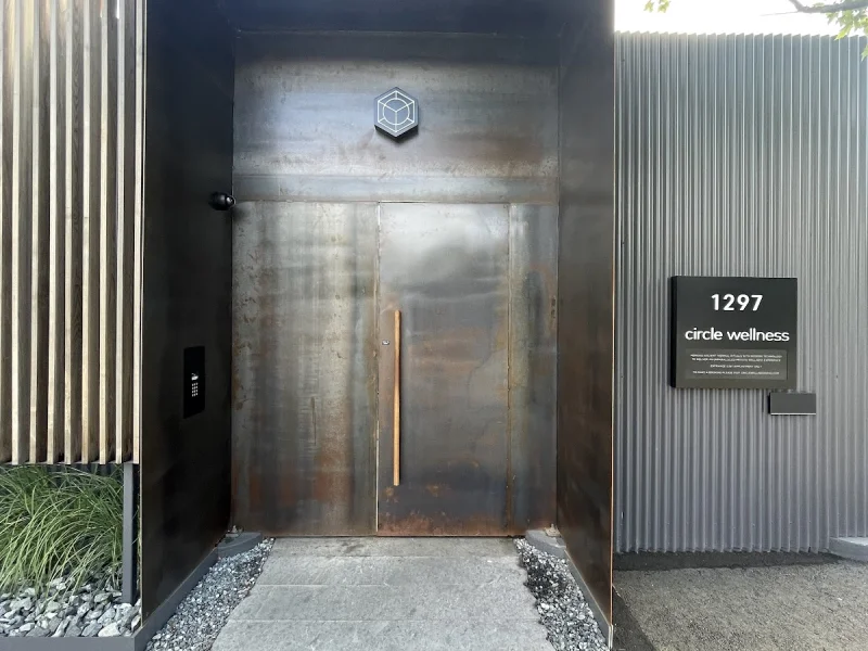 Modern steel entrance to Circle Wellness Granville Island with sculptural signage and greenery