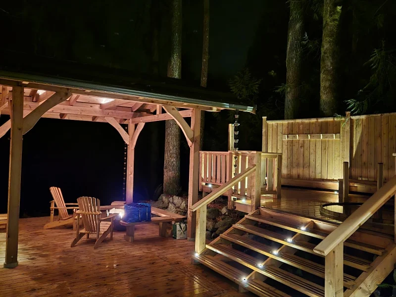 Nighttime outdoor sauna deck with fire pit and forest ambiance
