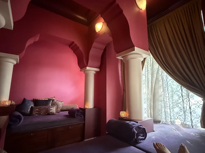 Deep burgundy treatment room with Moroccan arched doorways and cushioned massage beds